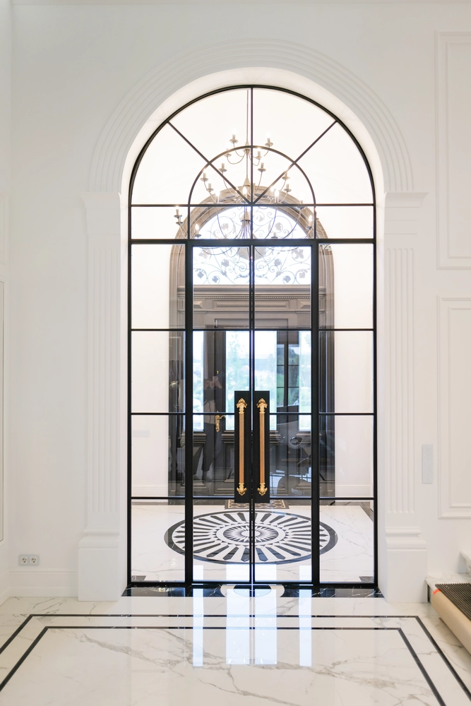 luxury entryway with arched steel doors and gold handles