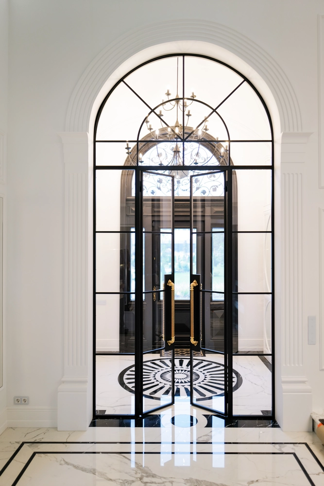 grand foyer featuring arched steel doors and gold handles